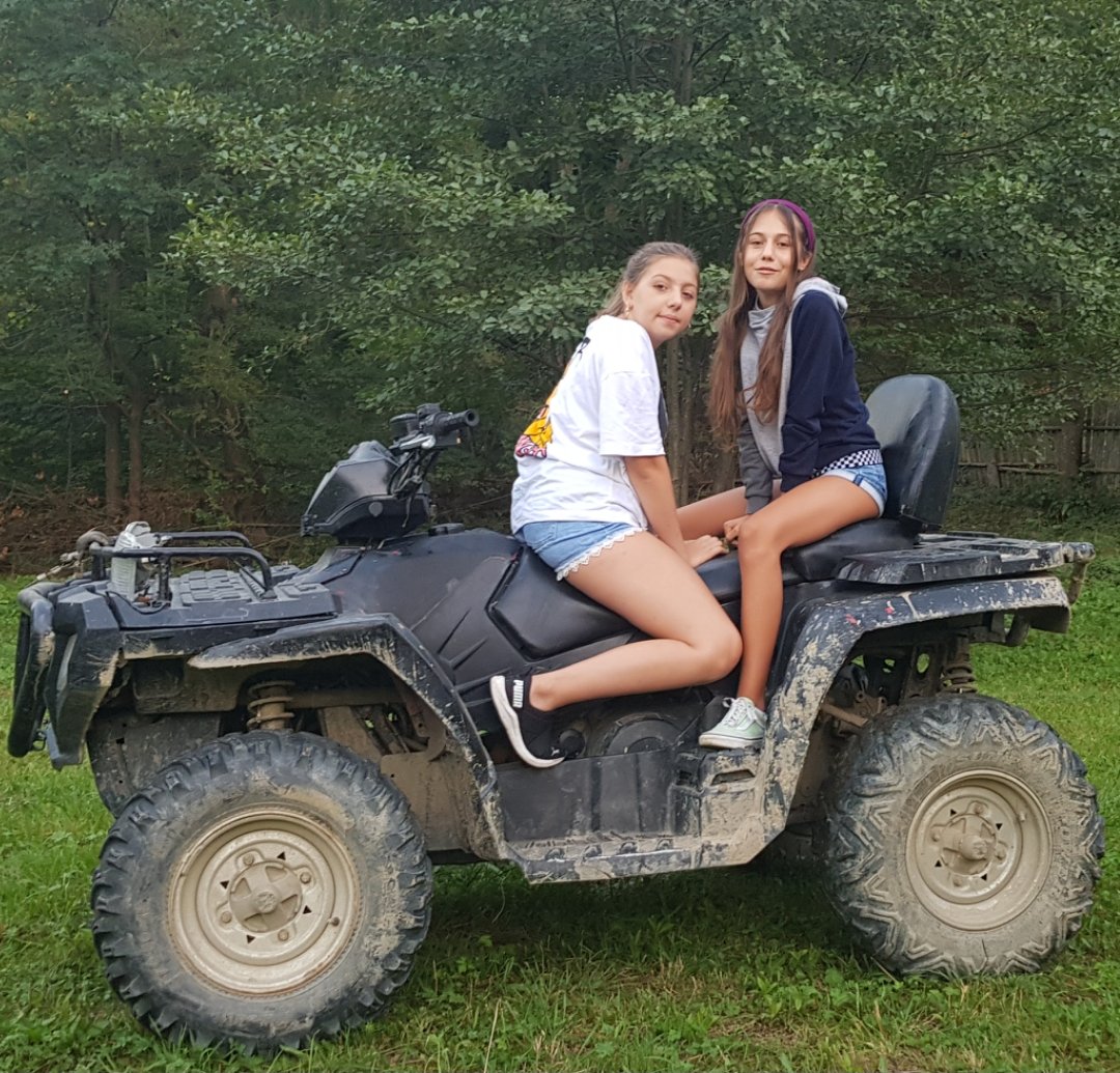 Two girls on an ATV, in the meadow near the guesthouse